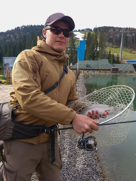 Pêche à la truite sur le lac. Pêcheur attrape une truite sur le lac — Photo