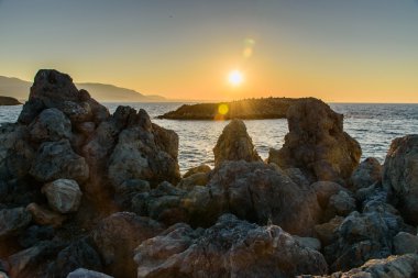 Akşam denizde güzel gün batımı kayalar ön planda