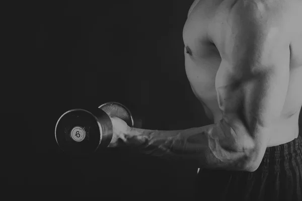 A man with a dumbbell on a black background — Stock Photo, Image