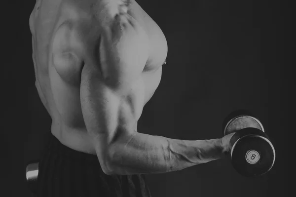 A man with a dumbbell on a black background — Stock Photo, Image