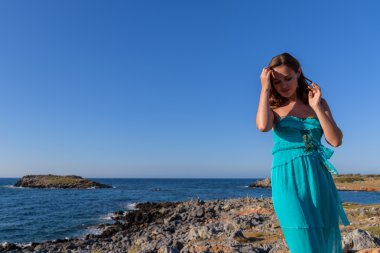 Mavi elbiseli bir sahilde güzel bir kız. Boş deniz at