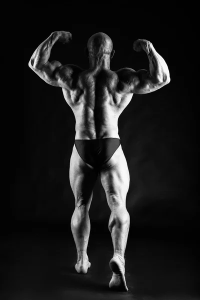 Bodybuilder posiert auf Schwarz — Stockfoto