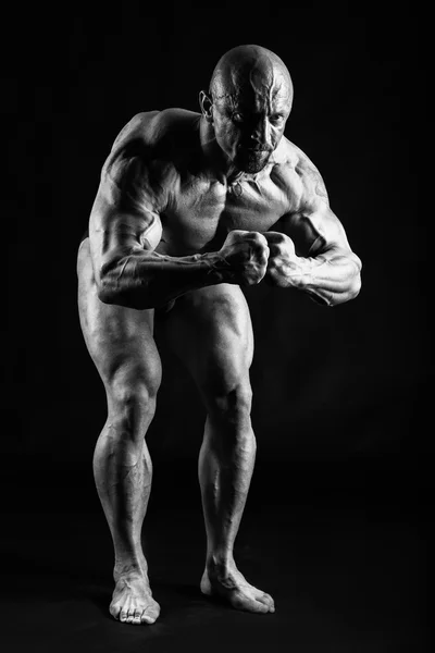 Bodybuilder posiert auf Schwarz — Stockfoto