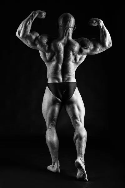 Bodybuilder posiert auf Schwarz — Stockfoto