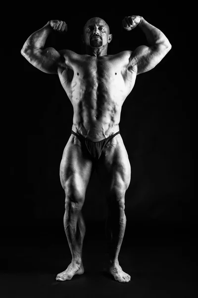 Bodybuilder posiert auf Schwarz — Stockfoto