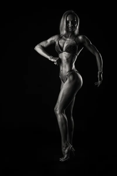 Elegant kvinna kroppsbyggare på svart — Stockfoto