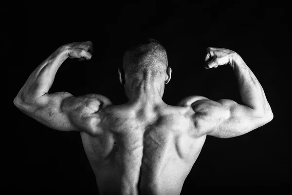 Fisiculturista posando em diferentes poses demonstrando seus músculos. Falha num fundo escuro. Homem mostrando músculos se esforçando. Bonito atleta corpo muscular . — Fotografia de Stock