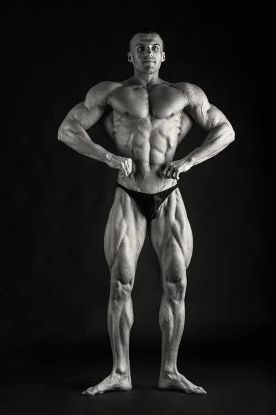 Fisiculturista posando em diferentes poses demonstrando seus músculos. Falha num fundo escuro. Homem mostrando músculos se esforçando. Bonito atleta corpo muscular . — Fotografia de Stock