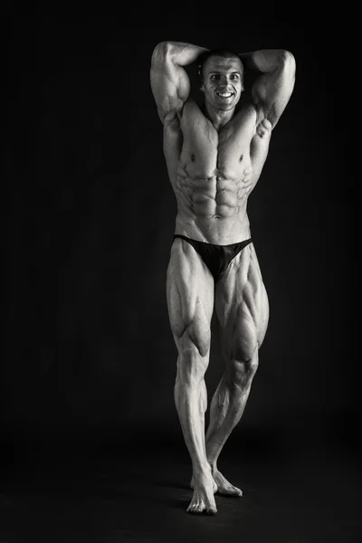 Fisiculturista posando em diferentes poses demonstrando seus músculos. Falha num fundo escuro. Homem mostrando músculos se esforçando. Bonito atleta corpo muscular . — Fotografia de Stock