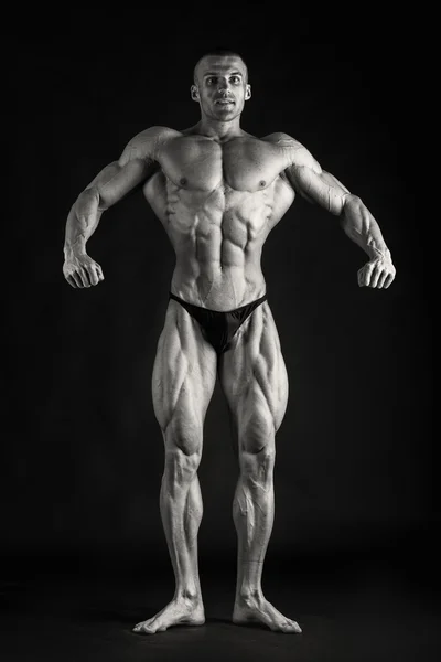 Fisiculturista posando em diferentes poses demonstrando seus músculos. Falha num fundo escuro. Homem mostrando músculos se esforçando. Bonito atleta corpo muscular . — Fotografia de Stock