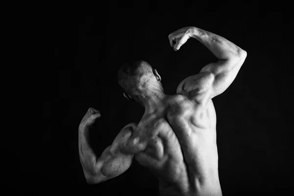 Fisiculturista posando em diferentes poses demonstrando seus músculos. Falha num fundo escuro. Homem mostrando músculos se esforçando. Bonito atleta corpo muscular . — Fotografia de Stock