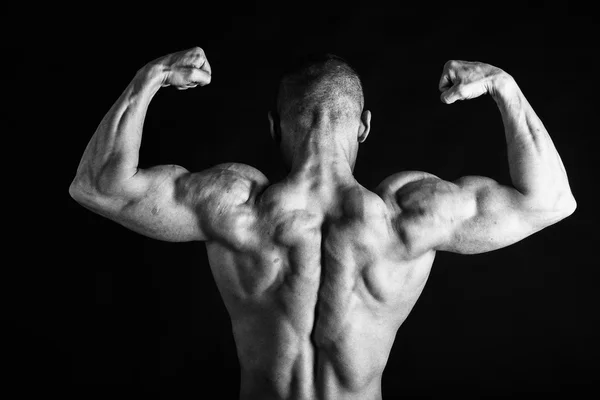 Fisiculturista posando em diferentes poses demonstrando seus músculos. Falha num fundo escuro. Homem mostrando músculos se esforçando. Bonito atleta corpo muscular . — Fotografia de Stock