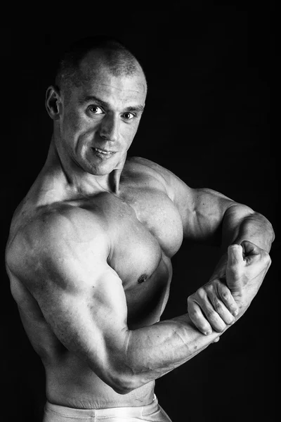 Culturista posando en diferentes poses demostrando sus músculos. Fracaso en un fondo oscuro. Varón mostrando tensión muscular. Hermoso atleta cuerpo muscular . — Foto de Stock