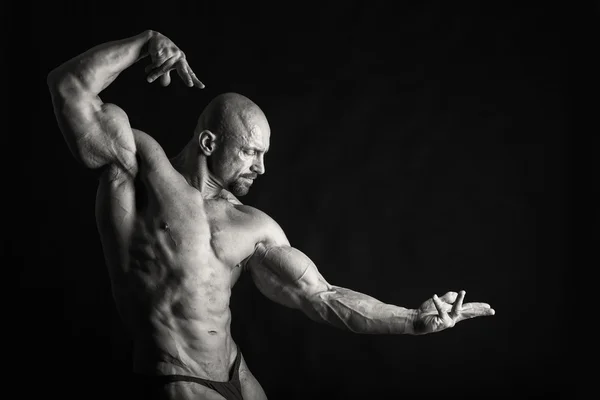 Fisiculturista posando em diferentes poses demonstrando seus músculos. Falha num fundo escuro. Homem mostrando músculos se esforçando. Bonito atleta corpo muscular . — Fotografia de Stock