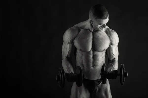 Culturista posando en diferentes poses demostrando sus músculos. Fracaso en un fondo oscuro. Varón mostrando tensión muscular. Hermoso atleta cuerpo muscular . —  Fotos de Stock