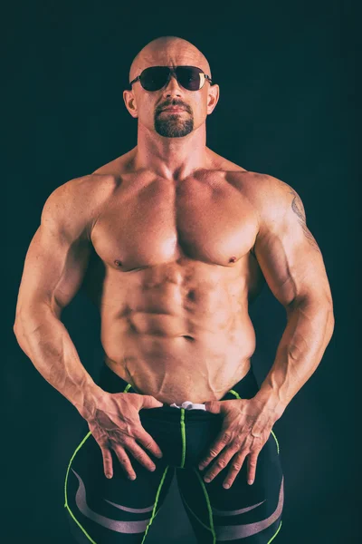 Selbstbewusster Bodybuilder auf dunklem Hintergrund. — Stockfoto