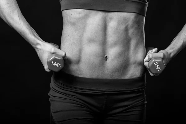 Fitness schöne Mädchen posiert auf einem schwarzen Hintergrund. — Stockfoto