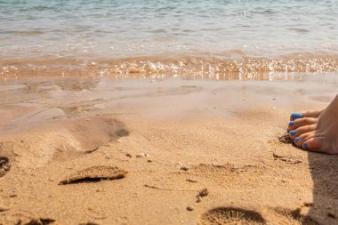 Manikürlü güzel bacaklar deniz kumlarında