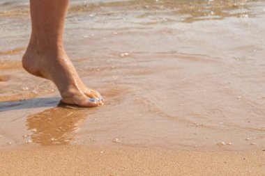 Manikürlü güzel bacaklar deniz kumlarında
