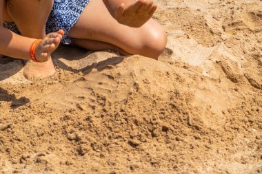 Çocuklar kumsalda kumla oynuyor.