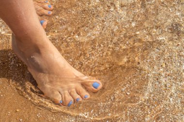 Manikürlü güzel bacaklar deniz kumlarında