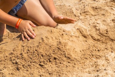 Çocuklar kumsalda kumla oynuyor.