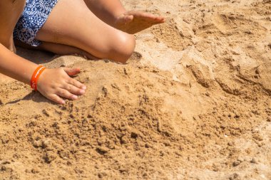 Çocuklar kumsalda kumla oynuyor.