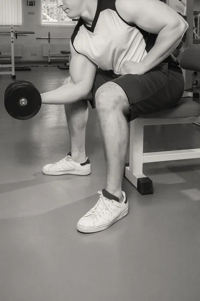 Homem faz exercícios com halteres . — Fotografia de Stock