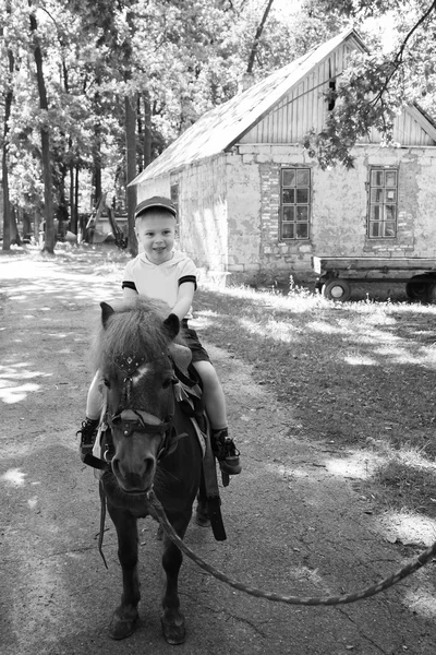 Kleine jongen rijden op een pony — Stockfoto