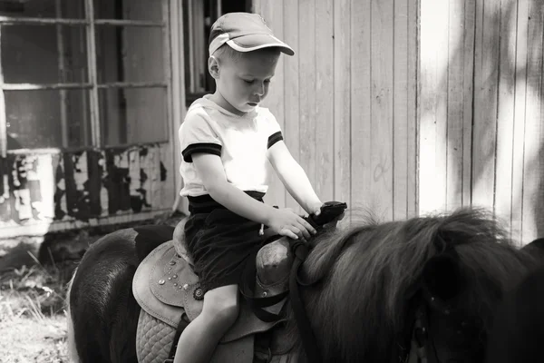 Kleine jongen rijden op een pony — Stockfoto