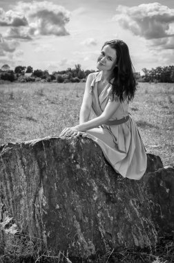 taş üzerine oturan esmer kadın