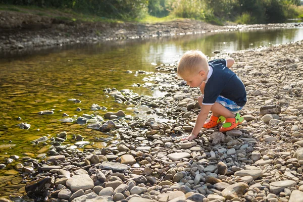 Poika heittelee kiviä veteen. — kuvapankkivalokuva