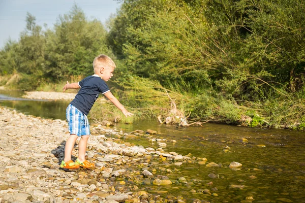 Boy throwing stones to the water