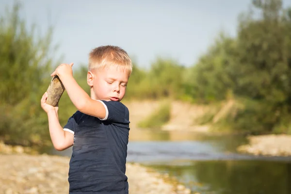 Boy throwing stones to the water — Stock Photo, Image