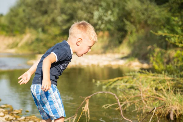 Boy throwing stones to the water — Stock Photo, Image