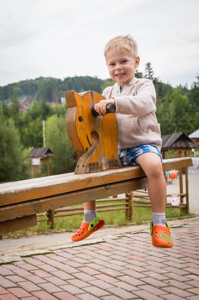 Мальчик на деревянных качелях - лошади — стоковое фото