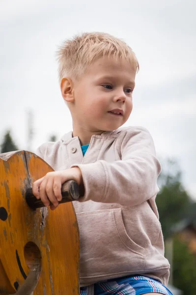 Niño en un columpio de madera - caballos —  Fotos de Stock