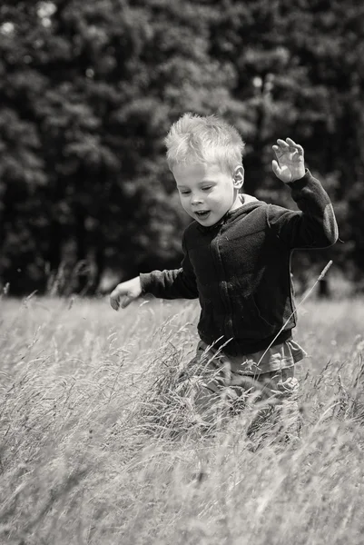 Liten pojke som körs på ett fält — Stockfoto