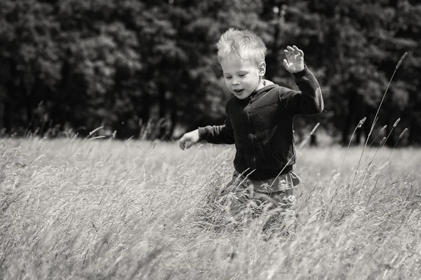 Liten pojke som körs på ett fält — Stockfoto