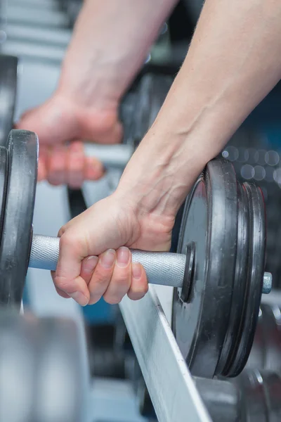 Muscular arm holding dumbbell — Stock Photo, Image