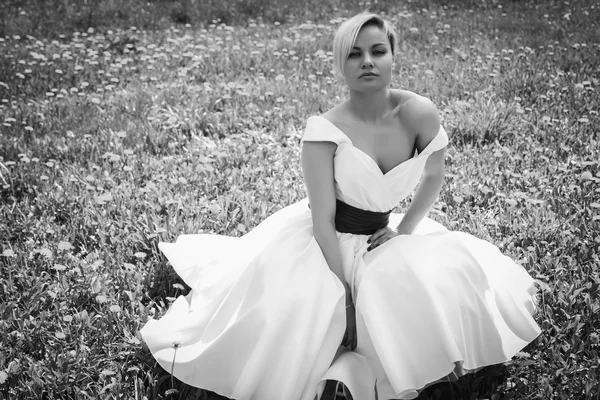 Loira em vestido branco no jardim da primavera — Fotografia de Stock