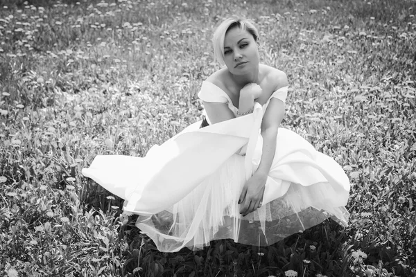 Blondýnka v bílých šatech v jarní zahradě — Stock fotografie
