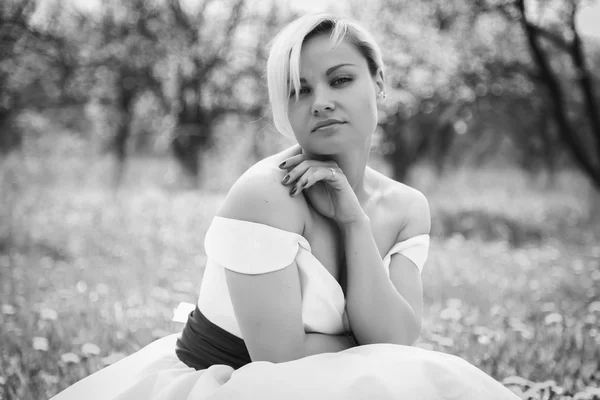 Loira em vestido branco no jardim da primavera — Fotografia de Stock