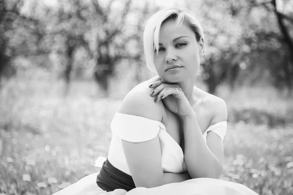 Loira em vestido branco no jardim da primavera — Fotografia de Stock