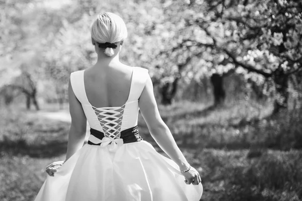 Rubia en vestido blanco en jardín de primavera — Foto de Stock