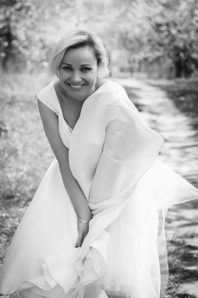 Rubia en vestido blanco en jardín de primavera — Foto de Stock