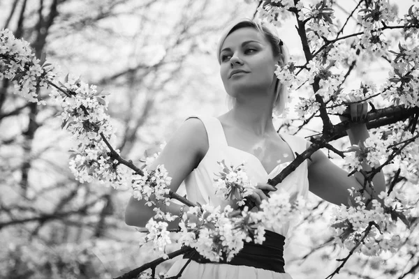 Blondýnka v bílých šatech v jarní zahradě — Stock fotografie