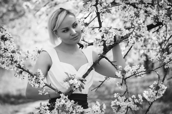 Blondine im weißen Kleid im Frühlingsgarten — Stockfoto