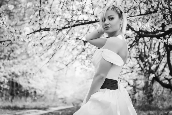 Blondin i vit klänning i vårträdgård — Stockfoto