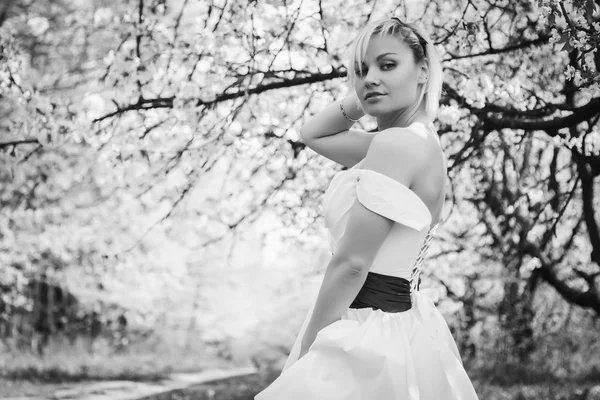 Rubia en vestido blanco en jardín de primavera — Foto de Stock